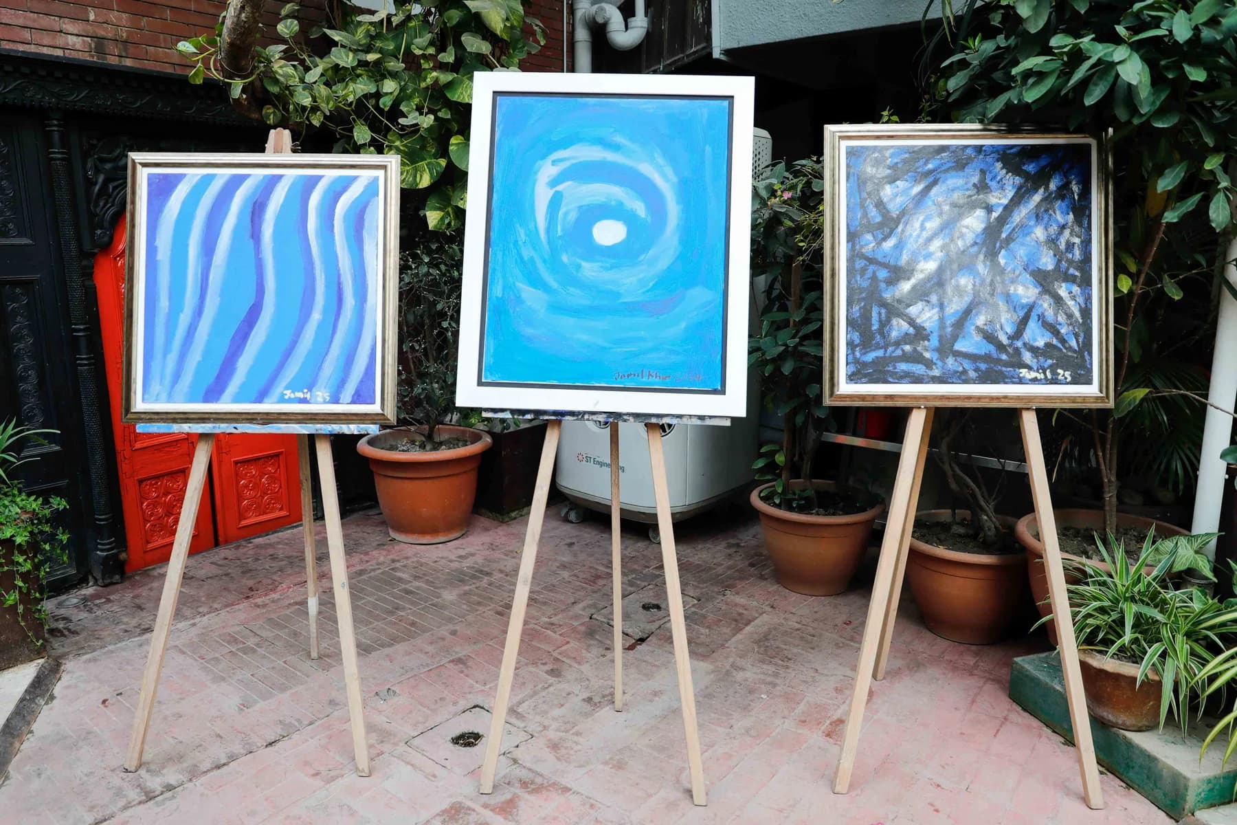 Blue paintings on easels in the courtyard — Imagination, a presentation of work by Jamil Khan at Gallery Cosmos