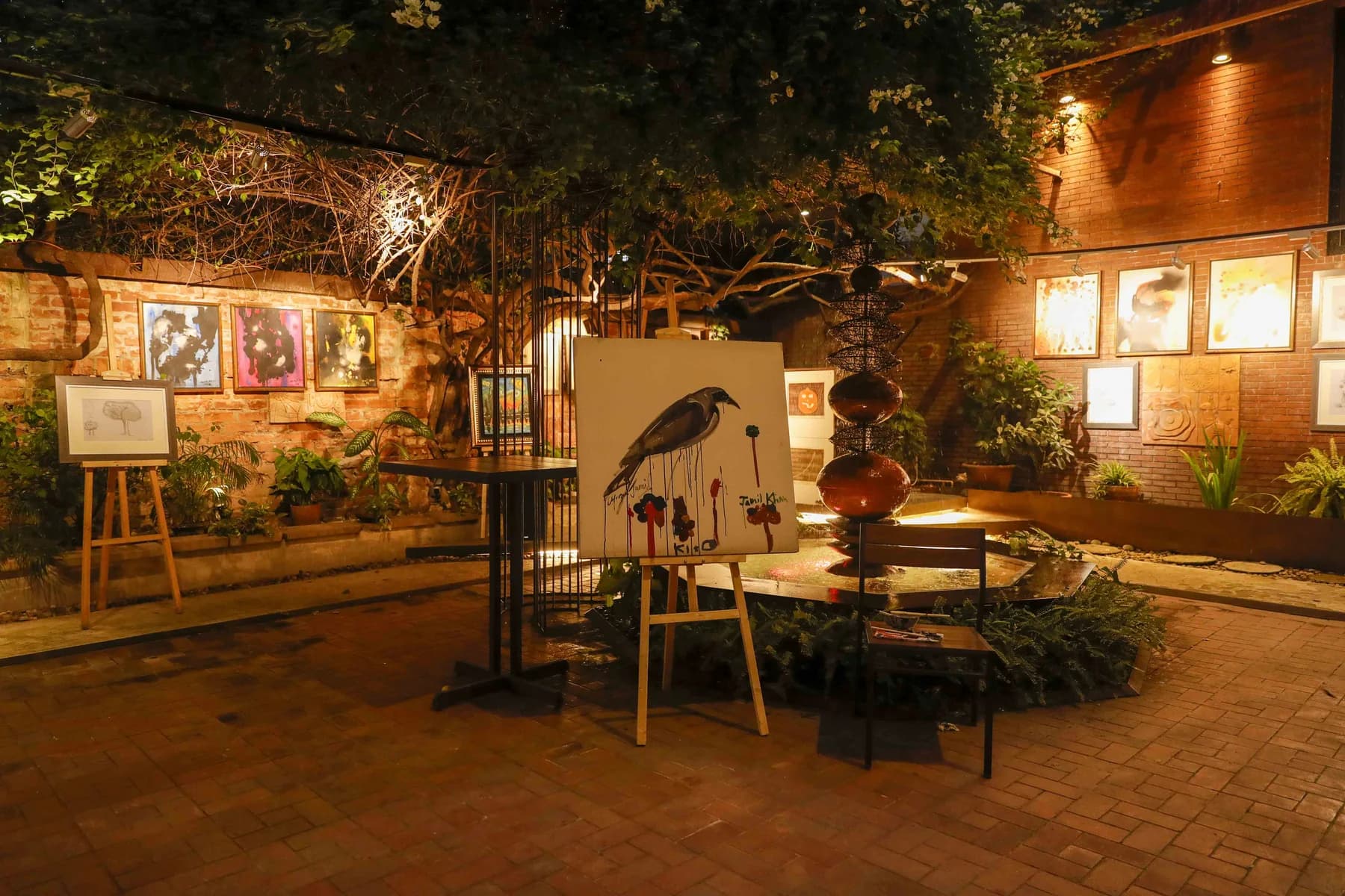 The gallery garden at night, with easels and lit works among the planting