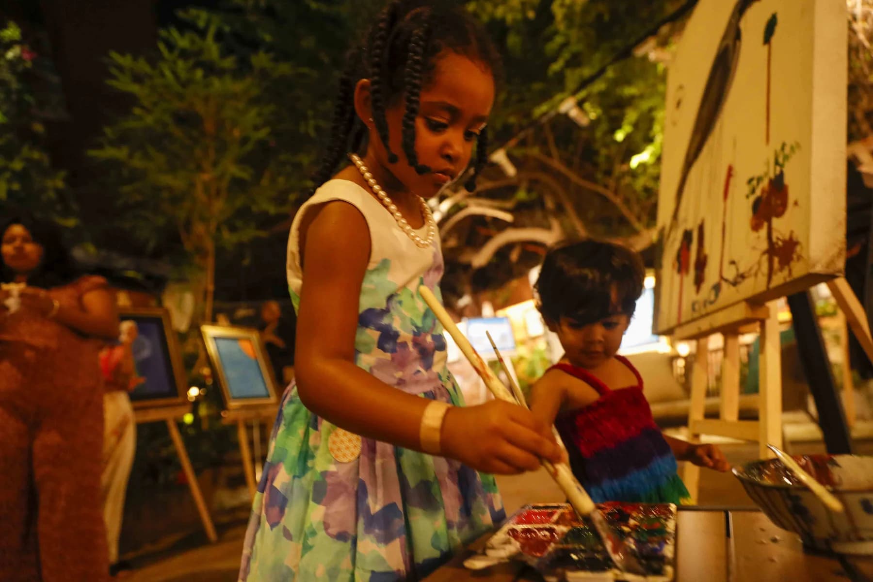 A young visitor painting at an easel — Inspiration, a solo exhibition by Jamil Khan at Gallery Cosmos
