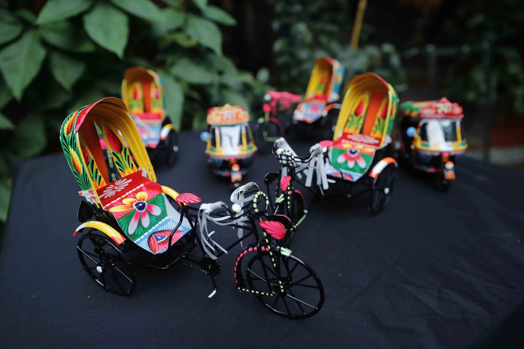 Miniature hand-painted rickshaws arranged on a dark cloth at the Rickshaw Art Exhibition